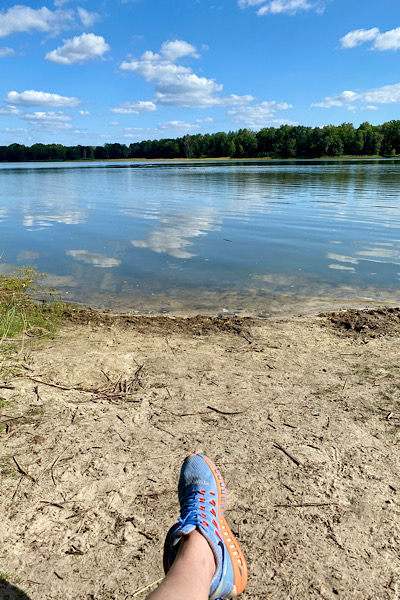 Ich sitze am Strand des Körbaer Sees und schaue entspannt auf die Wasseroberfläche.