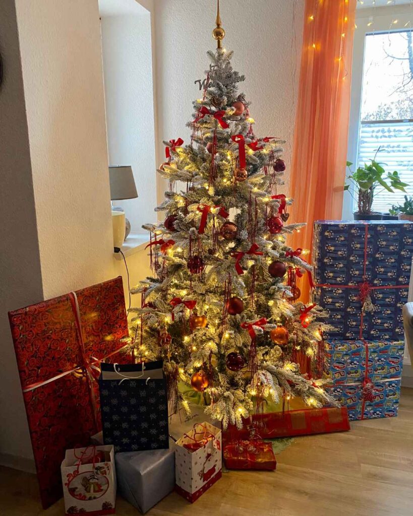 Unter dem festlich geschmückten Weihnachtsbaum liegen jede Menge große und kleine Geschenke.